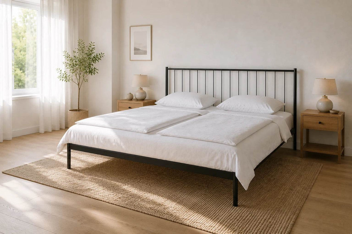 Metallbett 180 x 200 cm in schwarz in einem großzügigen, hellen Schlafzimmer mit zwei Nachttischen, zwei separaten Bettdecken und viel Raum um das Bett