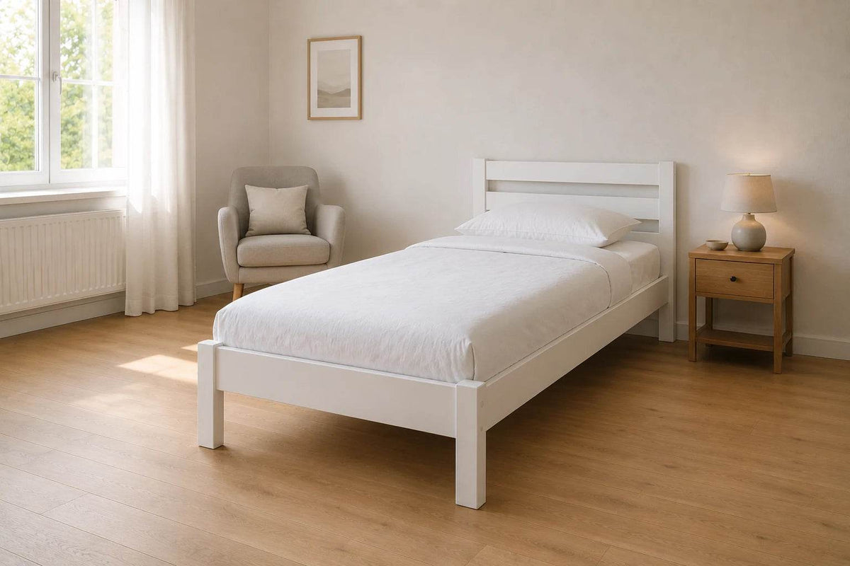 Massivholzbett 100 x 200 cm in weiß lackierter Buche mit Lesesessel, viel freier Bodenfläche und warmem Tageslicht