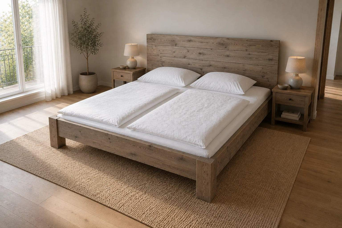 Massivholzbett 200 x 200 cm aus Wildeiche grau mit breitem Lamellen-Kopfteil in einem großzügigen hellen Schlafzimmer