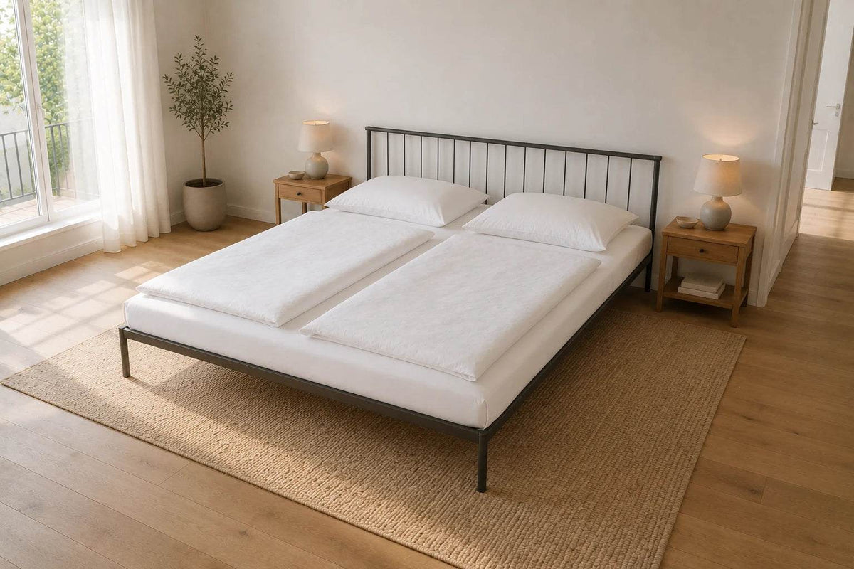 Metallbett 200 x 200 cm in dunkelgrau in einem großzügigen hellen Schlafzimmer mit zwei Nachttischen, zwei separaten Bettdecken und viel Raum um das Bett